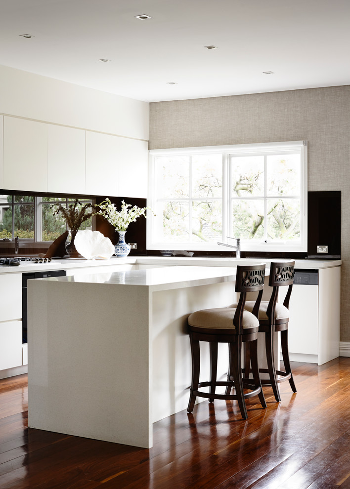 Design ideas for a small transitional l-shaped eat-in kitchen in Melbourne with an undermount sink, flat-panel cabinets, quartz benchtops, black splashback, glass sheet splashback, coloured appliances, medium hardwood floors and with island.