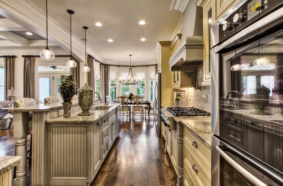 Design ideas for a large country kitchen in Nashville with a double-bowl sink, recessed-panel cabinets, beige cabinets, granite benchtops, grey splashback, stainless steel appliances, dark hardwood floors, with island and brown floor.