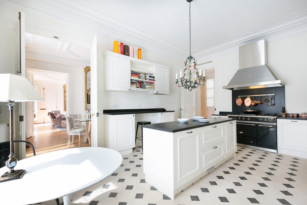 Expansive traditional l-shaped eat-in kitchen in Paris with white cabinets and with island.