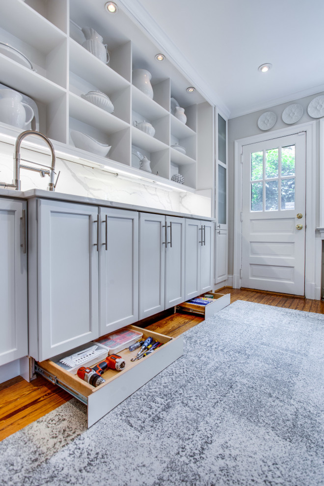 This is an example of a small transitional galley separate kitchen in DC Metro with an undermount sink, recessed-panel cabinets, quartz benchtops, engineered quartz splashback, medium hardwood floors and no island.