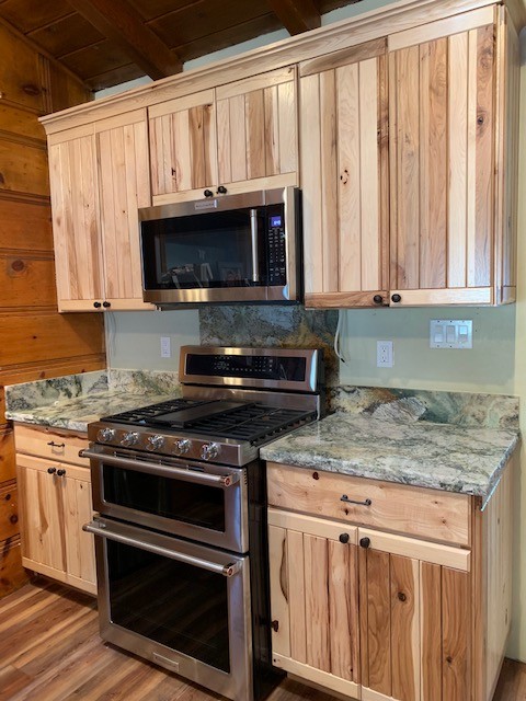 Inspiration for a mid-sized rustic medium tone wood floor and brown floor open concept kitchen remodel with an undermount sink, flat-panel cabinets, light wood cabinets, granite countertops, gray backsplash, stone slab backsplash, stainless steel appliances and gray countertops