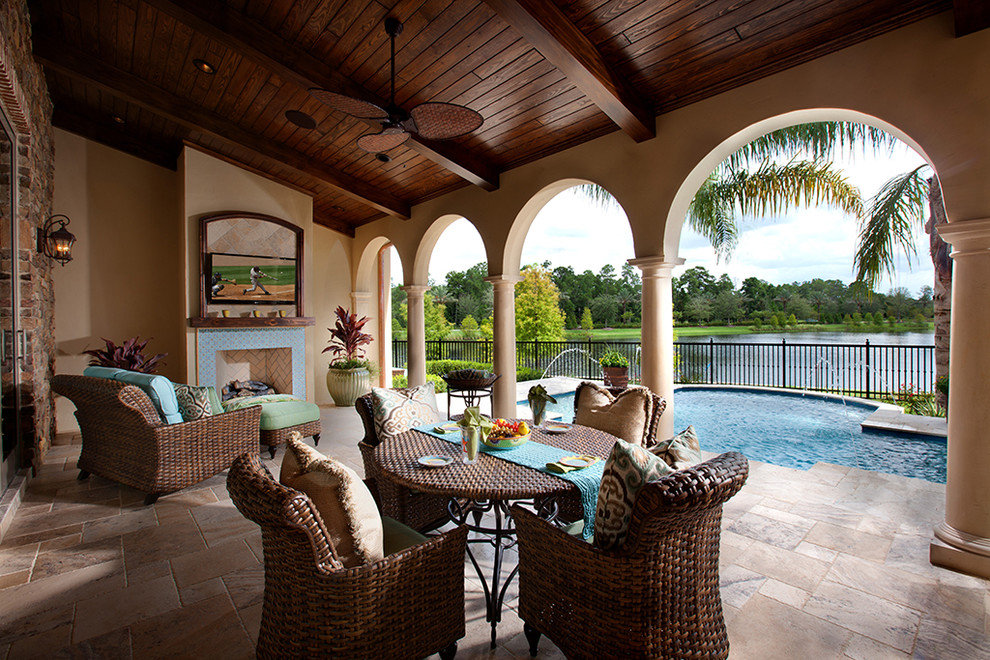 Large mediterranean backyard patio in Orlando with a fire feature, tile and a roof extension.