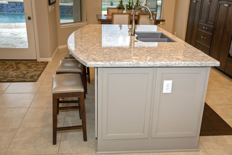 Transitional ceramic tile eat-in kitchen photo in Phoenix with an undermount sink, recessed-panel cabinets, dark wood cabinets, quartzite countertops, gray backsplash, stone tile backsplash, stainless steel appliances and an island