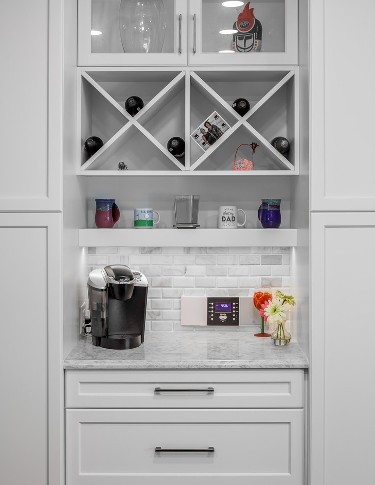 Brown floor eat-in kitchen photo with white cabinets, white backsplash, stainless steel appliances, an island and gray countertops
