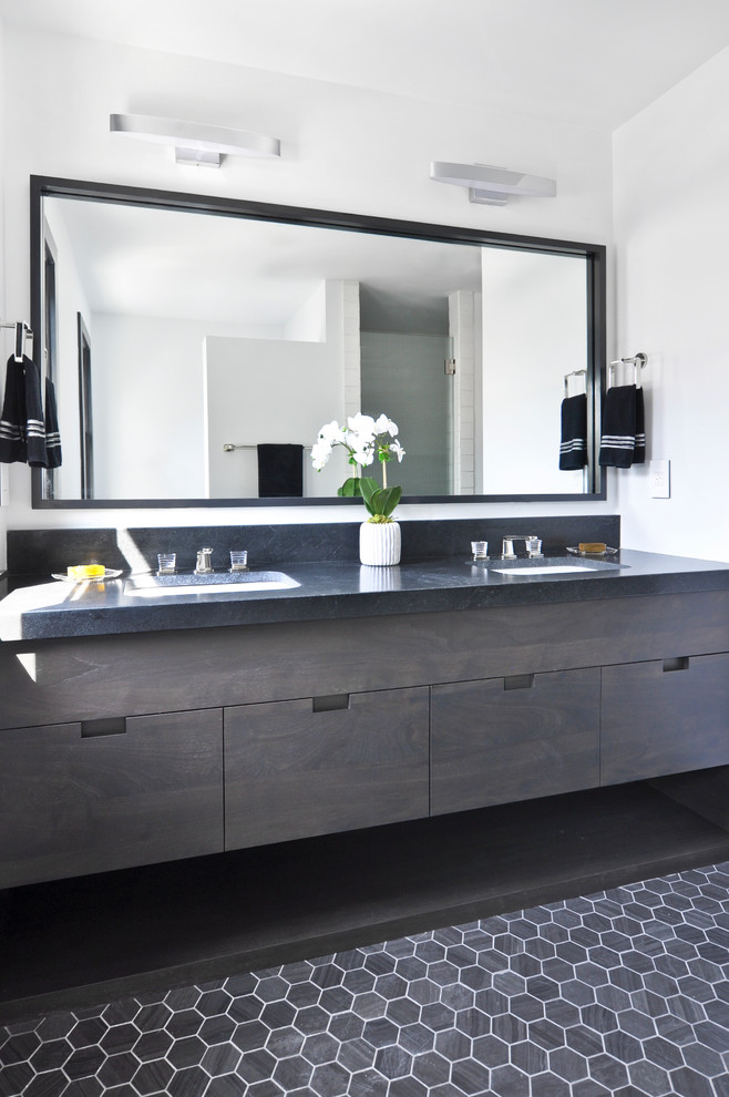 This is an example of a small contemporary master bathroom in Nashville with flat-panel cabinets, brown cabinets, a corner shower, a two-piece toilet, white tile, terra-cotta tile, white walls, limestone floors, an undermount sink, granite benchtops, black floor, a hinged shower door and black benchtops.