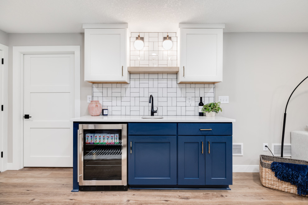 Example of a mid-sized 1950s single-wall vinyl floor and brown floor wet bar design in Other with an undermount sink, shaker cabinets, blue cabinets, quartzite countertops, white backsplash, porcelain backsplash and white countertops