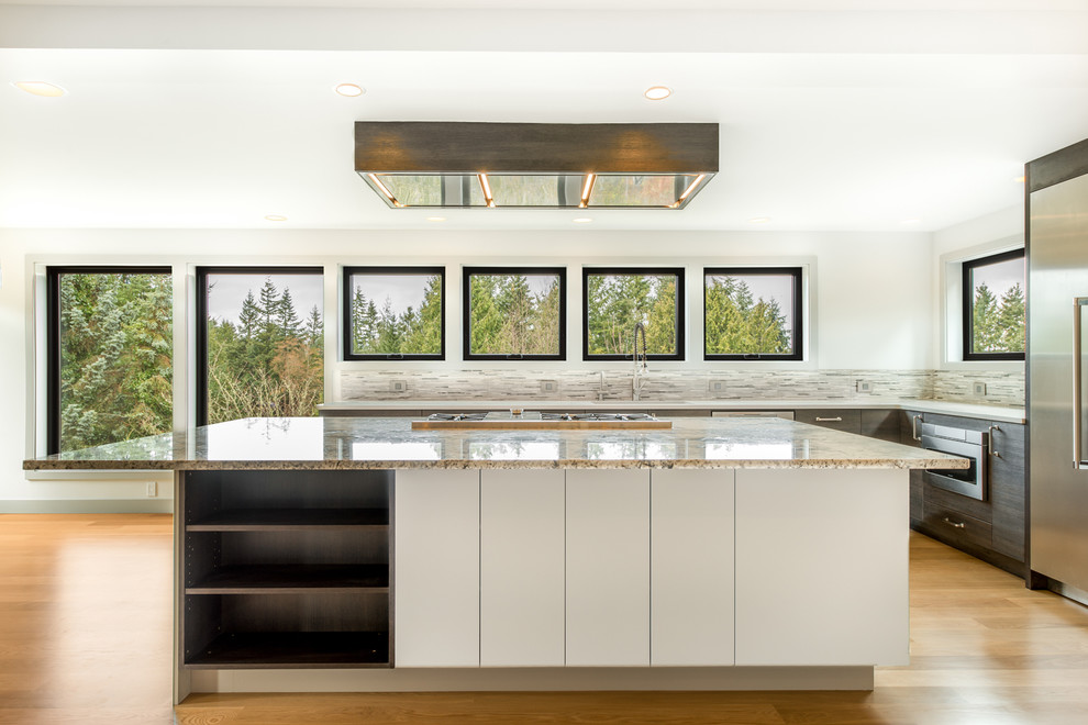 Large transitional u-shaped light wood floor and beige floor open concept kitchen photo in Seattle with an undermount sink, flat-panel cabinets, dark wood cabinets, granite countertops, gray backsplash, matchstick tile backsplash, stainless steel appliances, an island and multicolored countertops