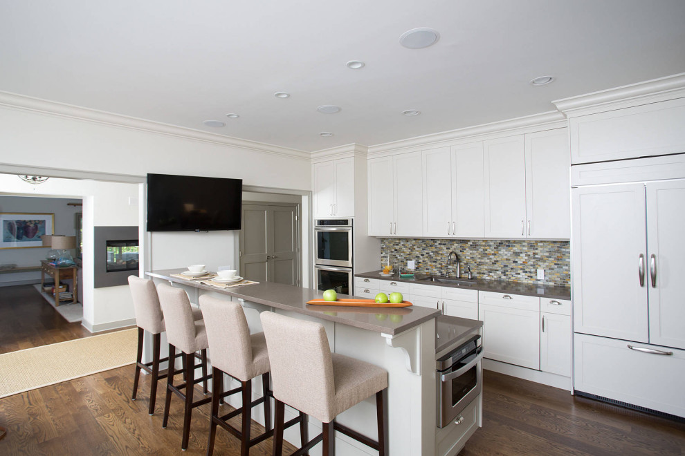 Esempio di una cucina design di medie dimensioni con lavello sottopiano, ante bianche, elettrodomestici in acciaio inossidabile e pavimento in legno massello medio