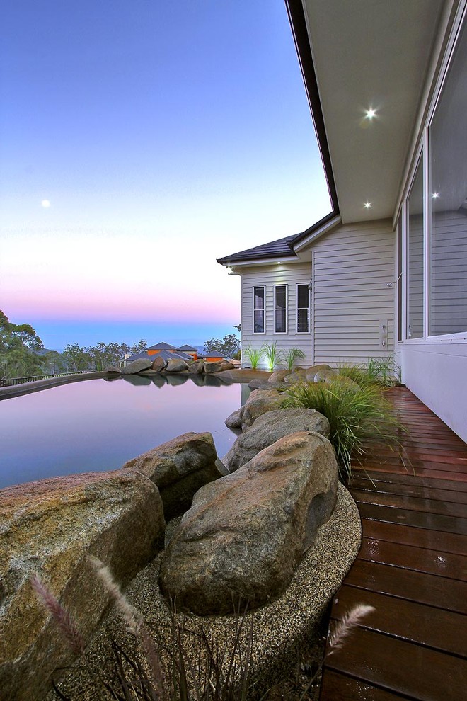 Inspiration for a mid-sized country courtyard custom-shaped natural pool in Brisbane with a water feature and natural stone pavers.