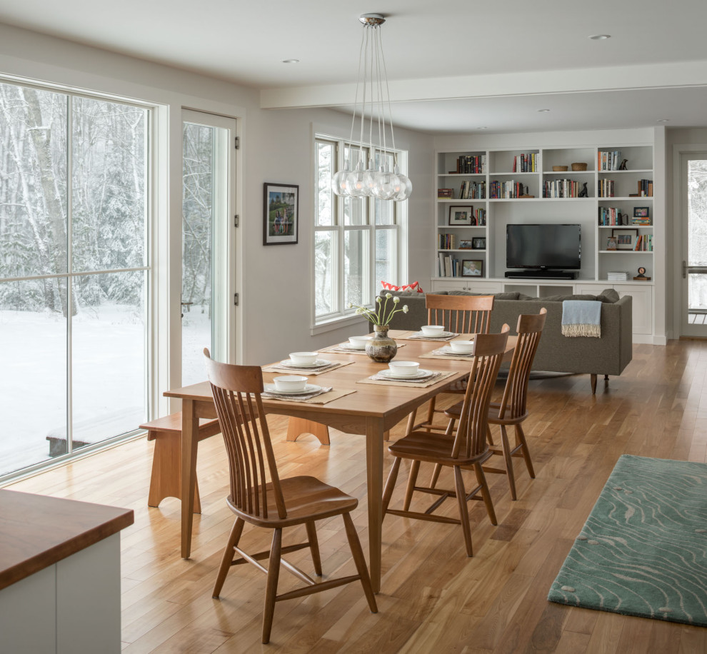 Mid-sized country medium tone wood floor and brown floor great room photo in Portland Maine with white walls