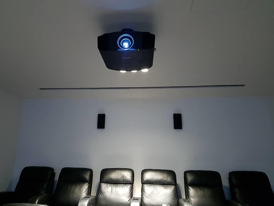 This is an example of a large modern home theatre in Sydney with grey walls and a projector screen.