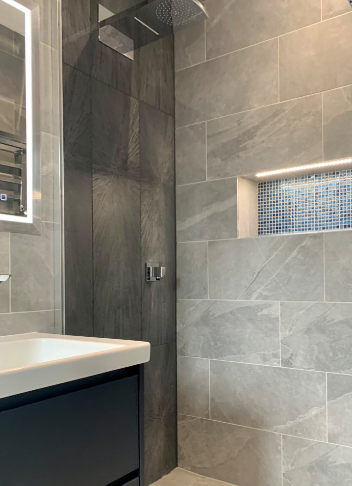 Inspiration for a mid-sized master wet room bathroom in Hertfordshire with flat-panel cabinets, blue cabinets, a wall-mount toilet, gray tile, porcelain tile, grey walls, porcelain floors, a wall-mount sink, grey floor, an open shower, a niche, a double vanity, a floating vanity and coffered.