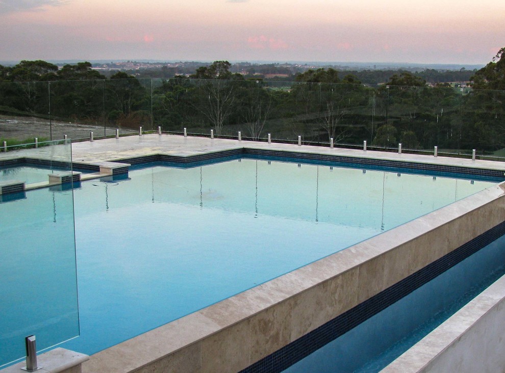 Photo of a large contemporary backyard custom-shaped lap pool in Sydney with natural stone pavers.