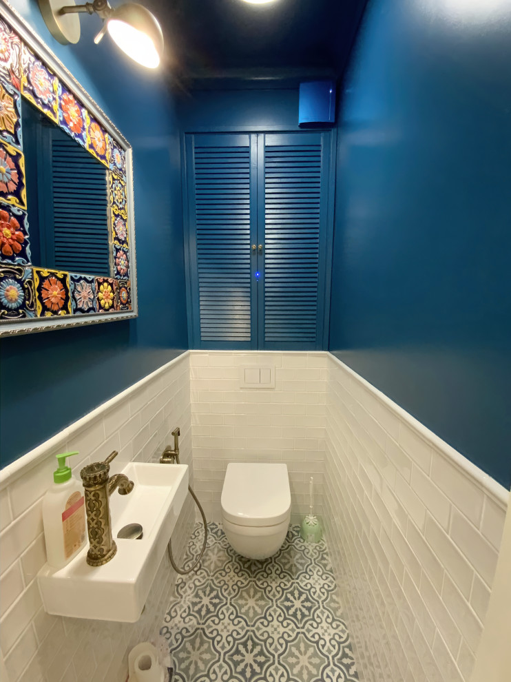 Esempio di un piccolo bagno di servizio con WC sospeso, pareti blu, pavimento con piastrelle in ceramica, lavabo sospeso e pavimento multicolore
