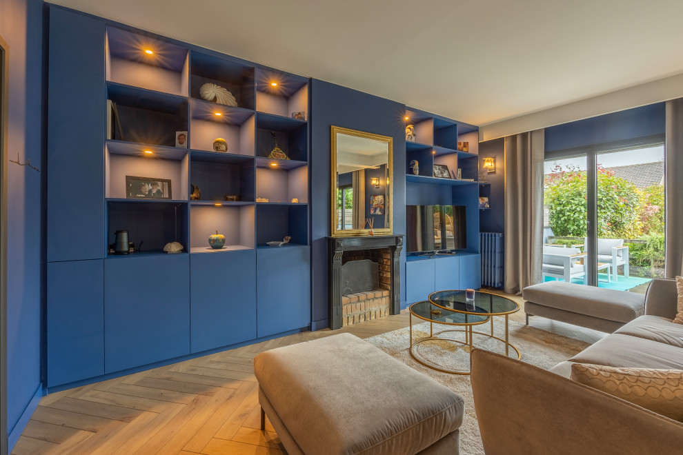 Large contemporary open concept living room in Le Havre with a library, blue walls, light hardwood floors, a standard fireplace, a plaster fireplace surround and a built-in media wall.