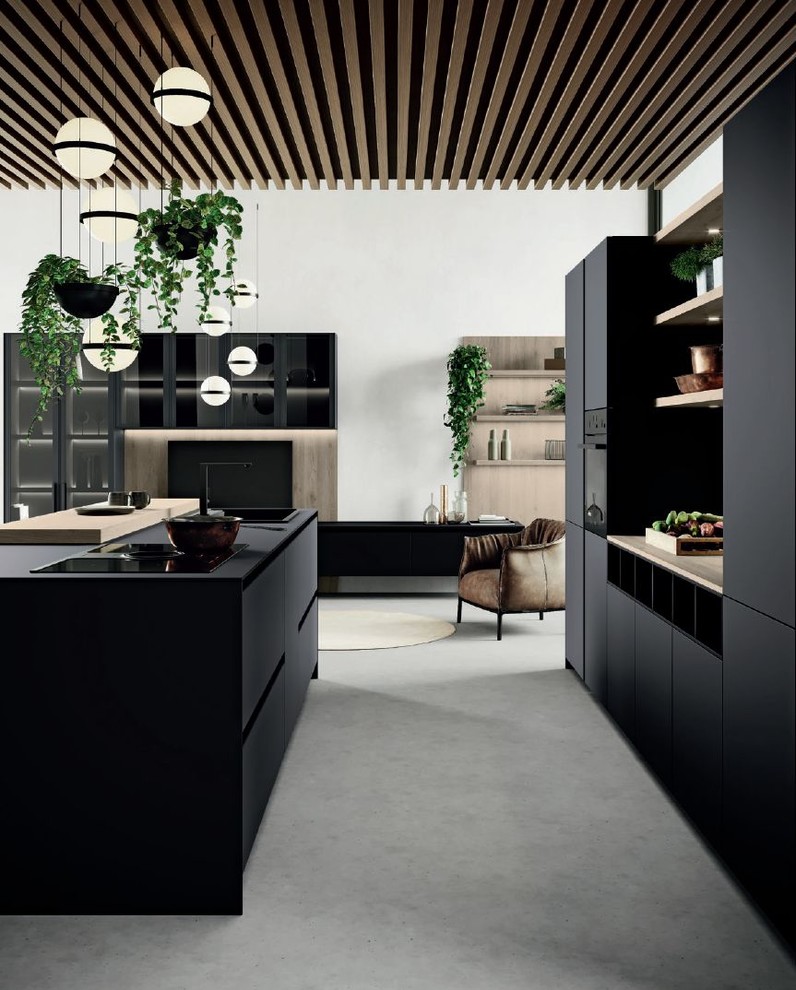 Inspiration for a mid-sized modern galley open plan kitchen in San Francisco with a drop-in sink, flat-panel cabinets, black cabinets, wood benchtops, black appliances, concrete floors, with island, grey floor and brown benchtop.