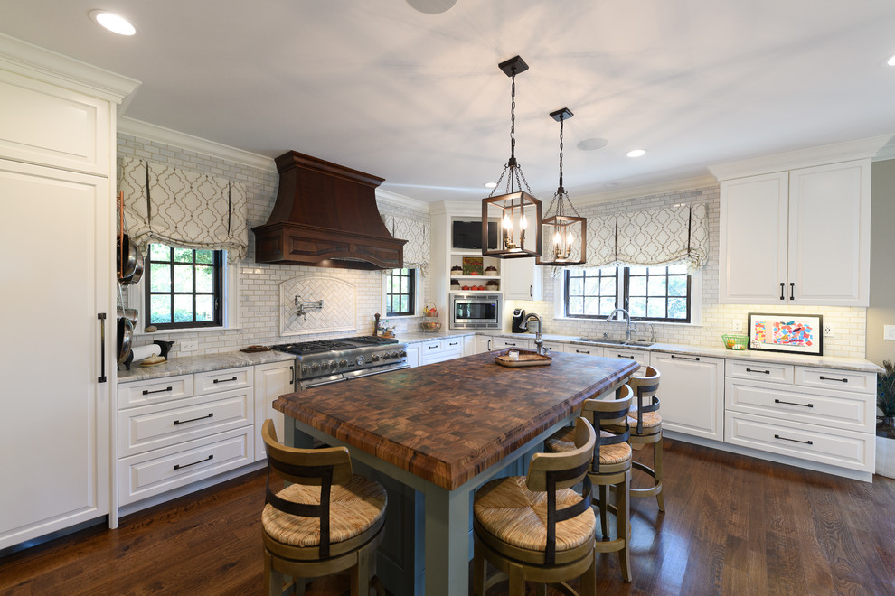 Kitchen - large transitional l-shaped dark wood floor and brown floor kitchen idea with an undermount sink, raised-panel cabinets, white cabinets, quartzite countertops, white backsplash, marble backsplash, stainless steel appliances and an island