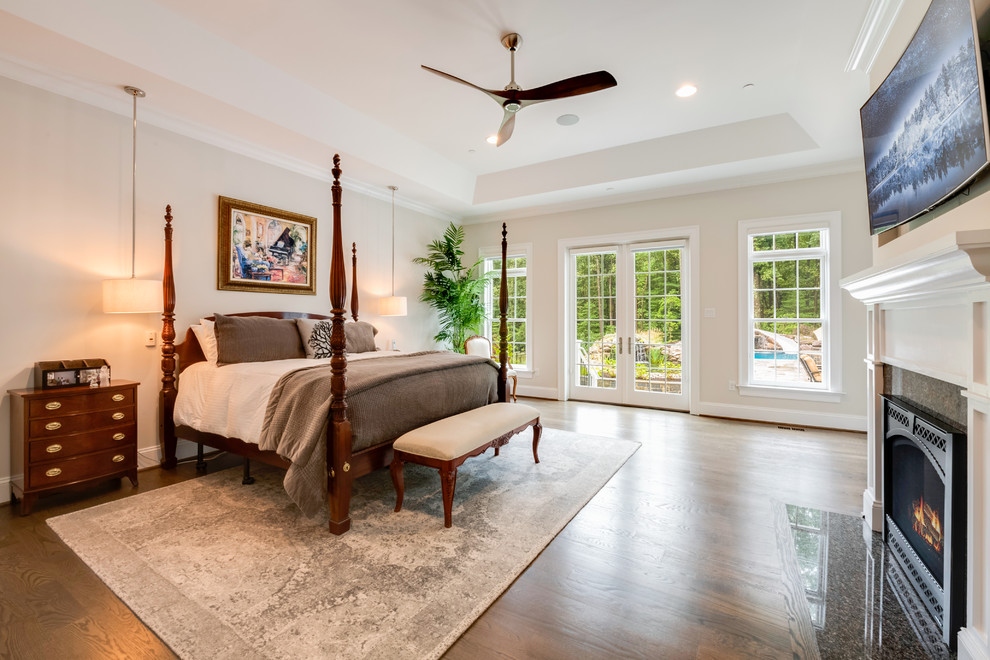 Inspiration for a large traditional master bedroom in Baltimore with beige walls, dark hardwood floors, a standard fireplace, a stone fireplace surround and brown floor.
