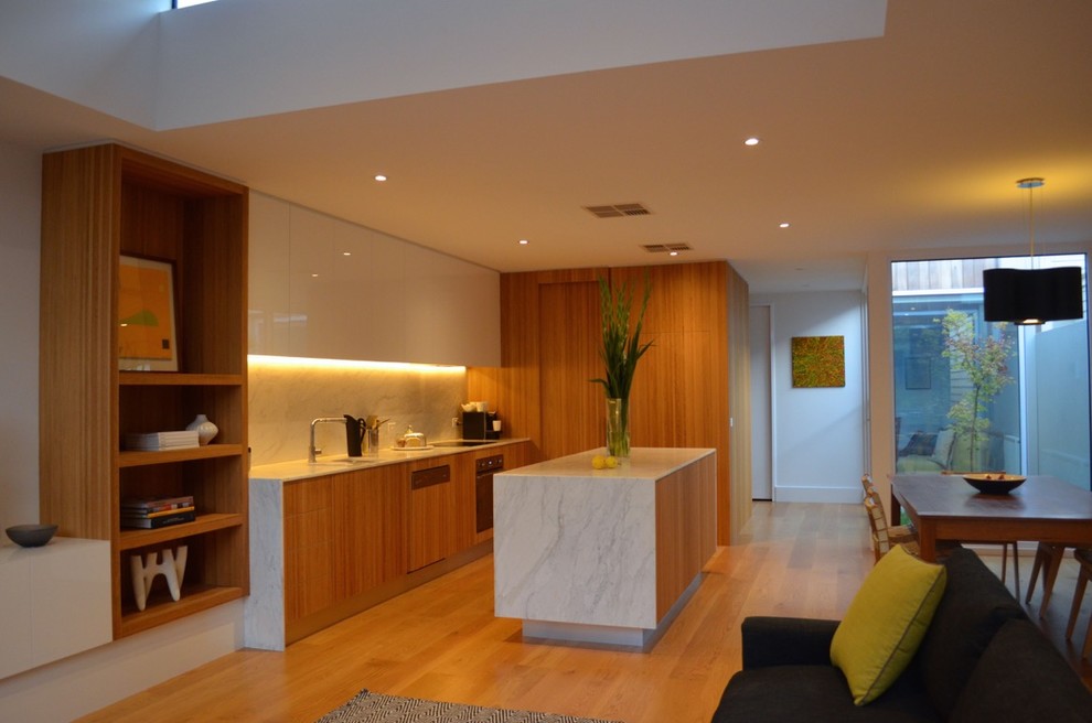Mid-sized contemporary single-wall eat-in kitchen in Melbourne with medium wood cabinets, marble benchtops, light hardwood floors, with island, an undermount sink, flat-panel cabinets, white splashback, marble splashback and stainless steel appliances.