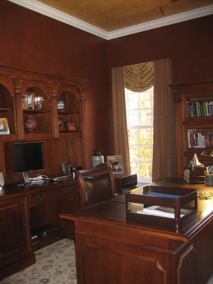 Large traditional study room in Raleigh with brown walls, dark hardwood floors, no fireplace, a freestanding desk and brown floor.