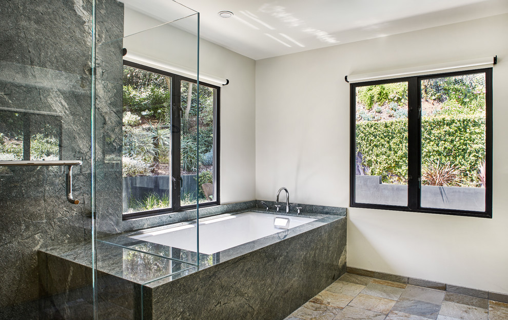 Design ideas for a mid-sized country master bathroom in Los Angeles with flat-panel cabinets, light wood cabinets, an undermount tub, a shower/bathtub combo, a one-piece toilet, green tile, stone slab, white walls, slate floors, an undermount sink, quartzite benchtops, beige floor, a hinged shower door and green benchtops.