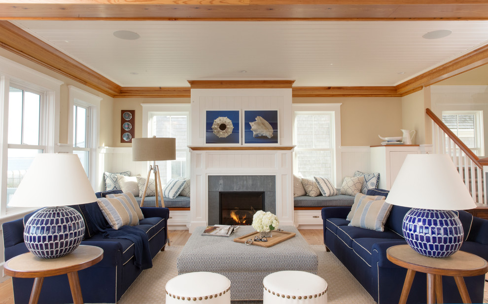 Photo of a large beach style formal open concept living room in Boston with beige walls, a standard fireplace, medium hardwood floors, a stone fireplace surround, no tv and beige floor.