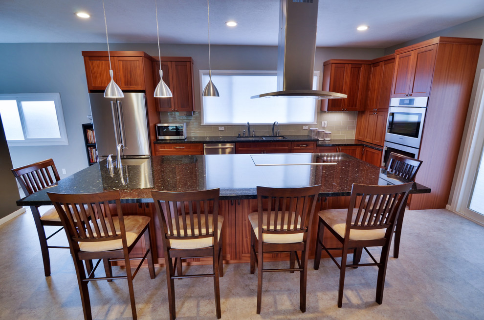 Photo of a mid-sized arts and crafts l-shaped open plan kitchen in Hawaii with a double-bowl sink, shaker cabinets, medium wood cabinets, granite benchtops, grey splashback, glass tile splashback, stainless steel appliances and with island.