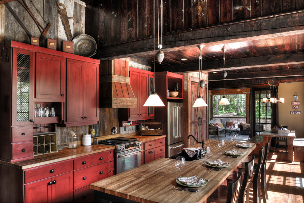 Photo of a mid-sized country galley eat-in kitchen in Minneapolis with a farmhouse sink, red cabinets, wood benchtops, stainless steel appliances, medium hardwood floors, with island, shaker cabinets, brown splashback, timber splashback and brown floor.