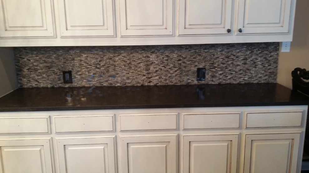 Example of a large transitional brown floor open concept kitchen design in Dallas with an undermount sink, raised-panel cabinets, white cabinets, granite countertops, gray backsplash, stone tile backsplash, stainless steel appliances and an island