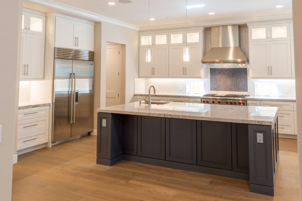 Eat-in kitchen - mid-sized transitional u-shaped medium tone wood floor and brown floor eat-in kitchen idea in San Francisco with an undermount sink, shaker cabinets, white cabinets, marble countertops, gray backsplash, stone tile backsplash, stainless steel appliances, an island and gray countertops