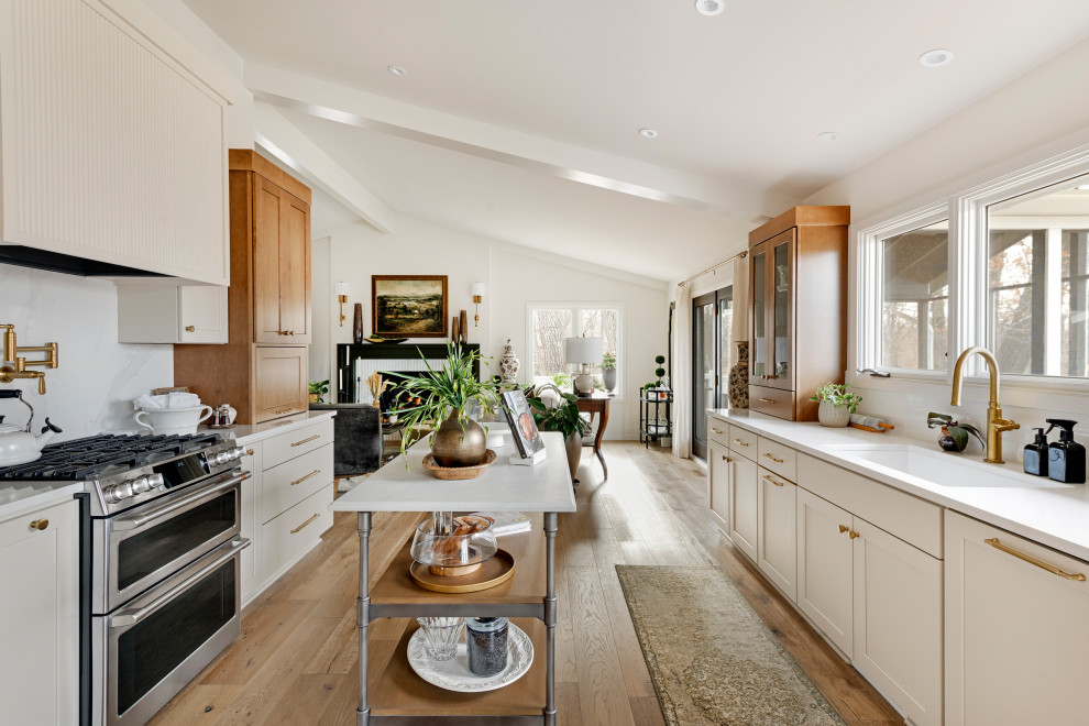 Mid-sized transitional galley medium tone wood floor, brown floor and vaulted ceiling eat-in kitchen photo in Minneapolis with an undermount sink, shaker cabinets, quartz countertops, white backsplash, subway tile backsplash, stainless steel appliances, an island and white countertops