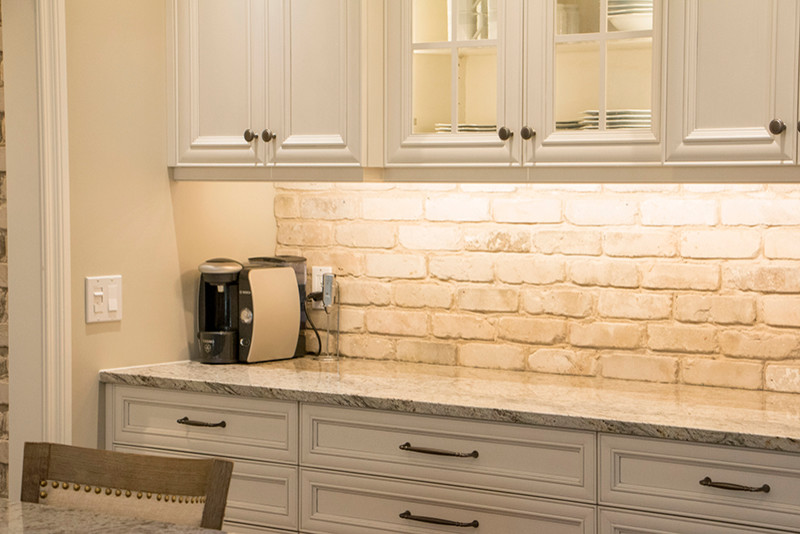 Large transitional l-shaped eat-in kitchen photo with a double-bowl sink, shaker cabinets, white cabinets, beige backsplash, stainless steel appliances and an island