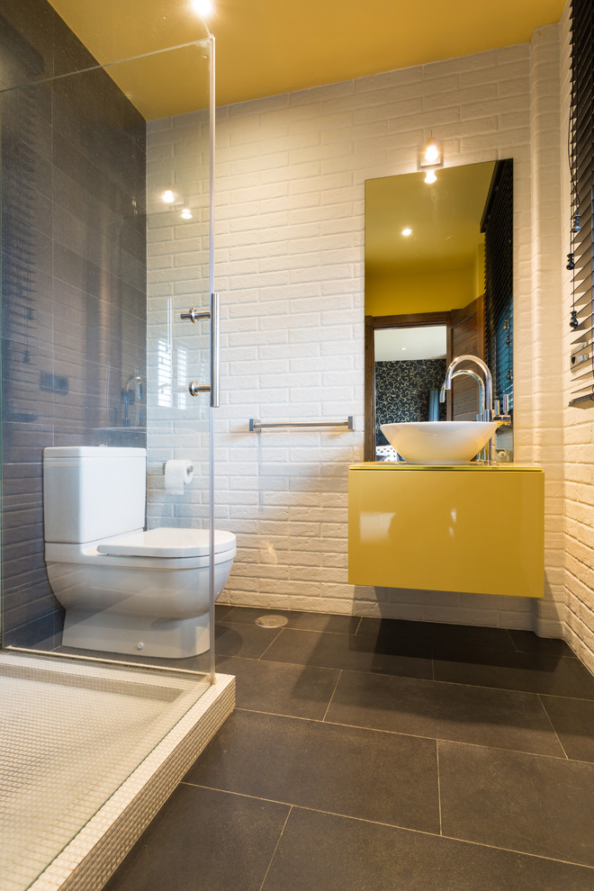 Design ideas for a mid-sized modern 3/4 bathroom in Other with flat-panel cabinets, yellow cabinets, a corner shower, a two-piece toilet, multi-coloured walls, ceramic floors and a vessel sink.