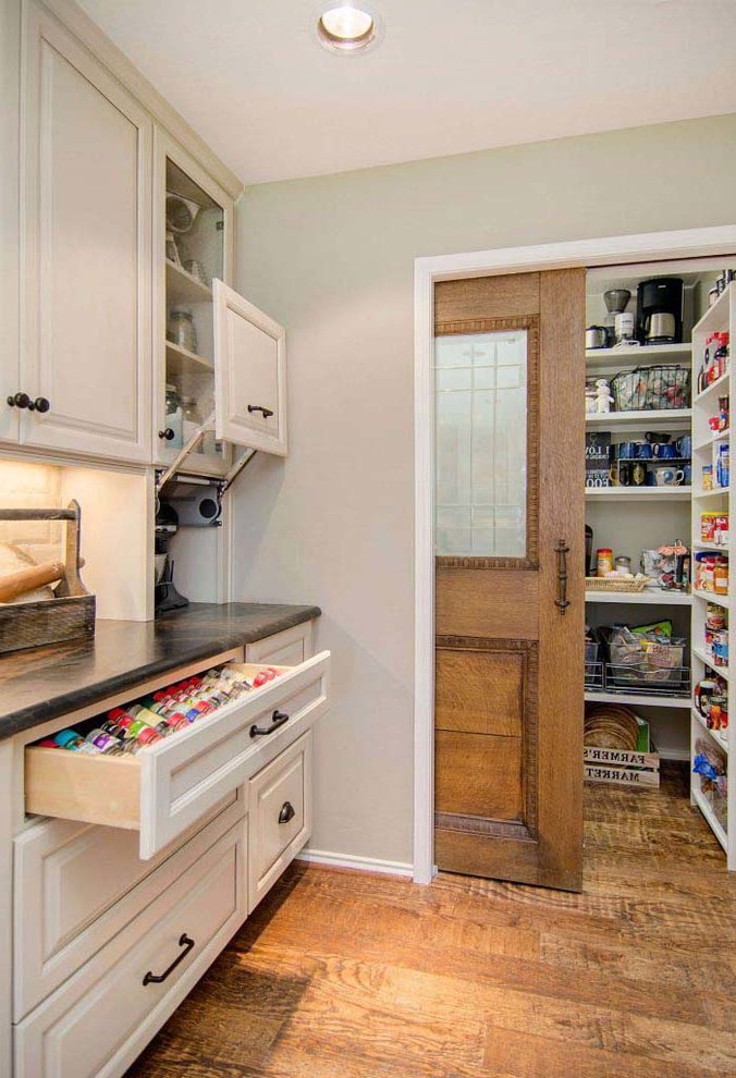 This is an example of a large traditional kitchen pantry in DC Metro with shaker cabinets, white cabinets, quartz benchtops, white splashback, ceramic splashback, stainless steel appliances, medium hardwood floors, brown floor and green benchtop.
