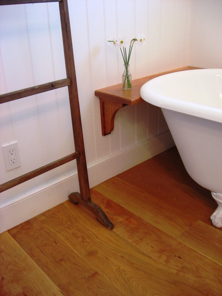 This is an example of a small traditional master bathroom in Boston with medium wood cabinets, a one-piece toilet, a claw-foot tub, white walls and medium hardwood floors.