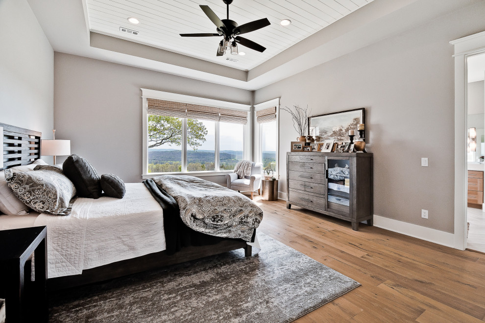 Large cottage master light wood floor, tray ceiling and shiplap wall bedroom photo in Other with gray walls