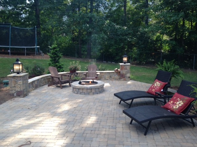 This is an example of a mid-sized country backyard patio in Atlanta with a fire feature, natural stone pavers and no cover.
