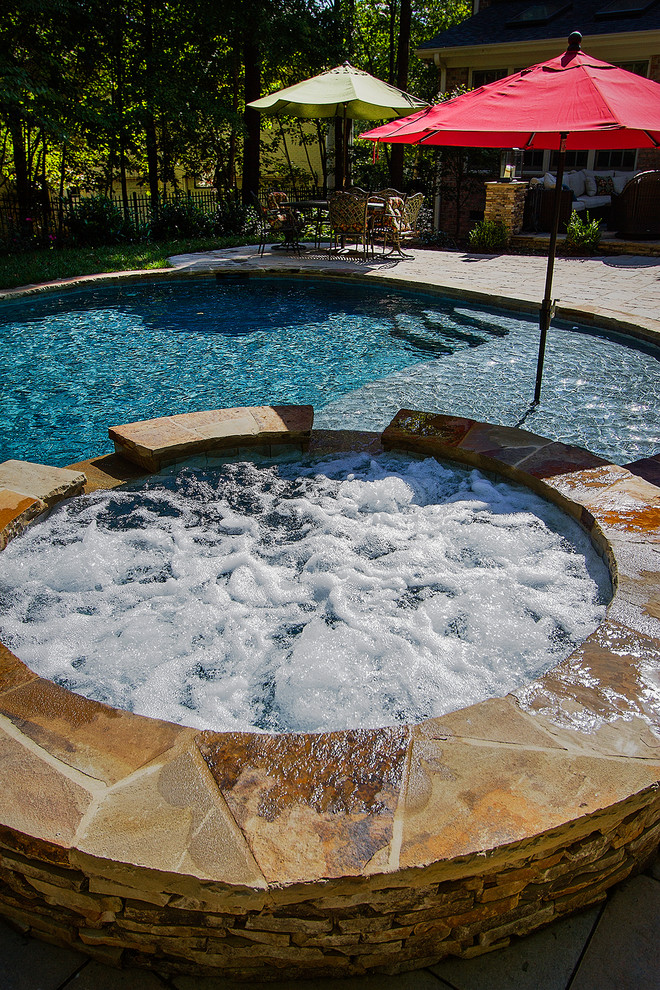 Hot tub - large rustic backyard concrete paver and custom-shaped natural hot tub idea in Raleigh