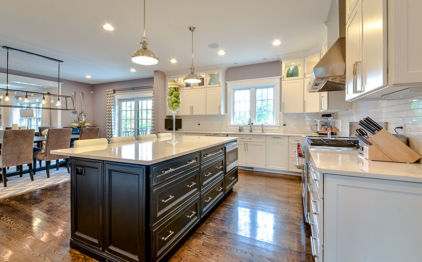 Inspiration for a mid-sized traditional l-shaped eat-in kitchen in Boston with shaker cabinets, white cabinets, granite benchtops, white splashback, subway tile splashback, dark hardwood floors, with island, stainless steel appliances and brown floor.