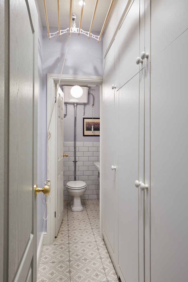 Bild på ett litet toalett, med en toalettstol med separat cisternkåpa, grå väggar, klinkergolv i porslin, ett piedestal handfat och beiget golv