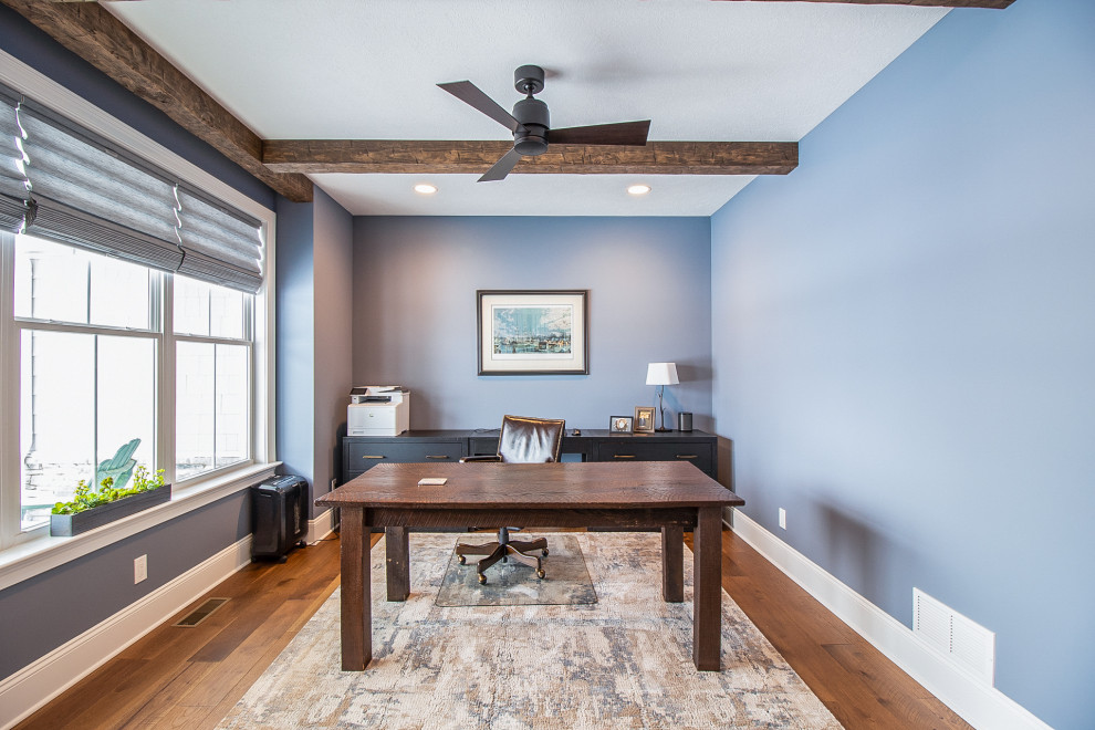 Cette image montre un grand bureau traditionnel avec un mur bleu, un sol en bois brun, un bureau indépendant, un sol marron et poutres apparentes.