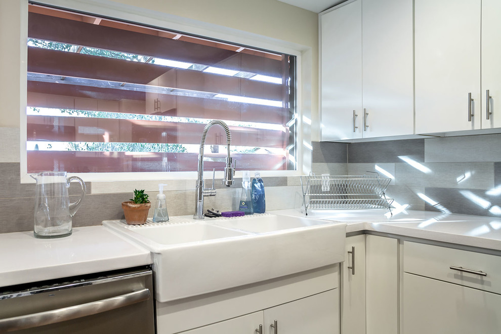 Open concept kitchen - transitional u-shaped porcelain tile open concept kitchen idea in Phoenix with a farmhouse sink, shaker cabinets, white cabinets, quartz countertops, multicolored backsplash, porcelain backsplash, stainless steel appliances and an island
