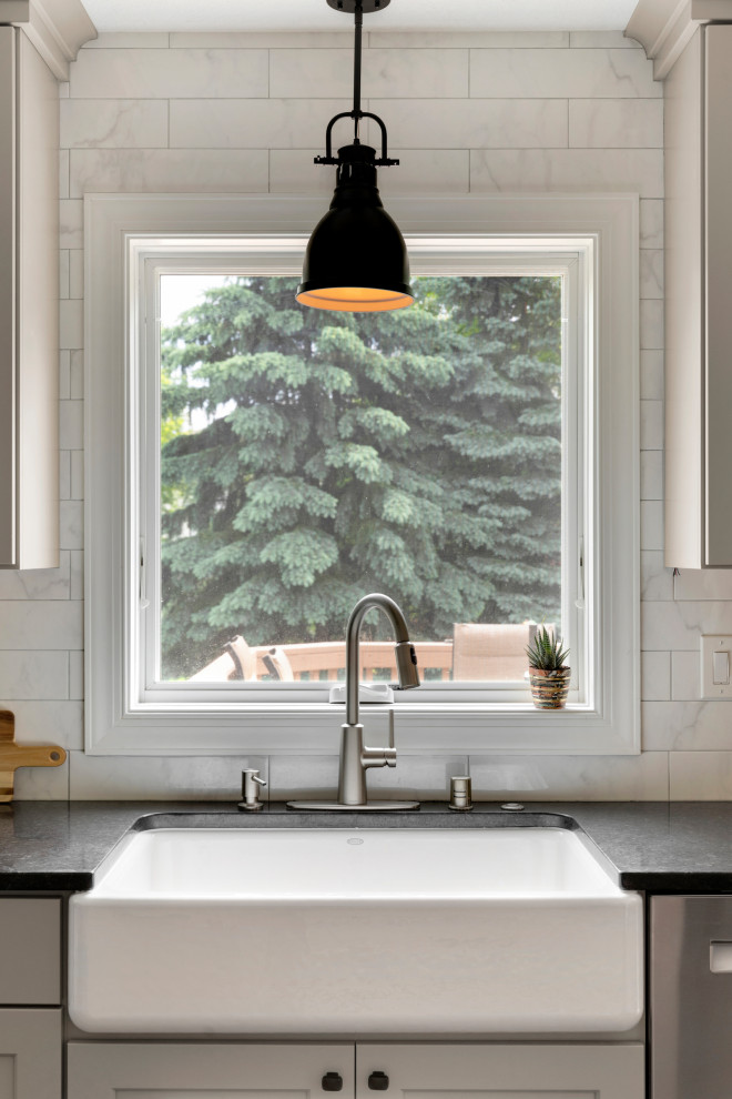 Inspiration for a large transitional single-wall eat-in kitchen in Minneapolis with a farmhouse sink, shaker cabinets, grey cabinets, quartz benchtops, white splashback, ceramic splashback, stainless steel appliances, vinyl floors, multiple islands, brown floor and black benchtop.