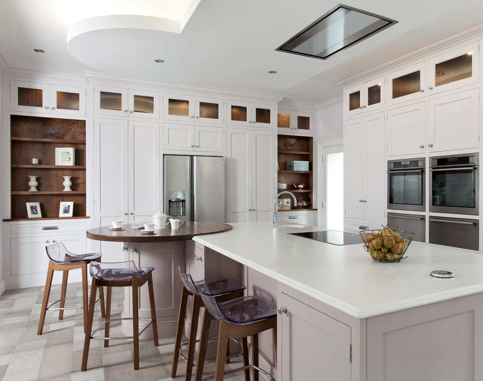 This is an example of a mid-sized transitional l-shaped open plan kitchen in Dublin with a farmhouse sink, shaker cabinets, yellow cabinets, quartzite benchtops, stainless steel appliances, with island and white benchtop.