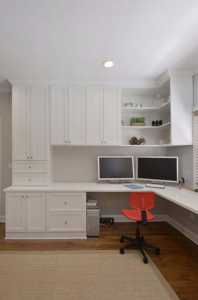 This is an example of a large contemporary home office in New York with white walls, medium hardwood floors and a built-in desk.