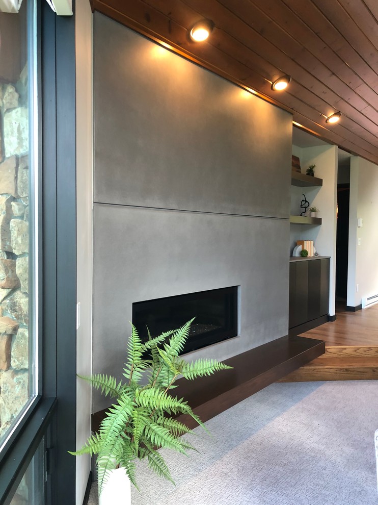 Photo of a large contemporary open concept family room in Denver with carpet, a ribbon fireplace, a concrete fireplace surround, no tv and grey floor.