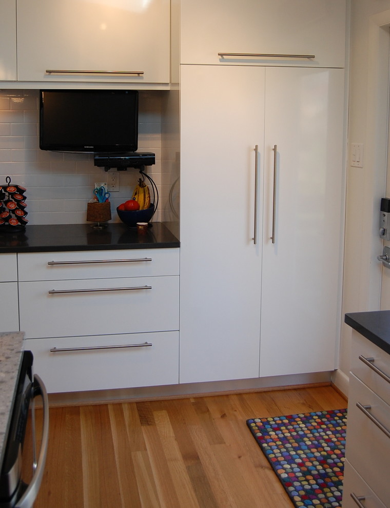 This is an example of a modern u-shaped eat-in kitchen in Other with an undermount sink, flat-panel cabinets, white cabinets, quartz benchtops, green splashback, glass tile splashback and stainless steel appliances.