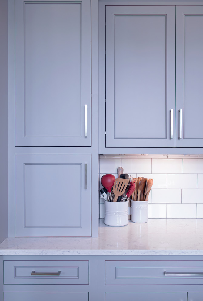 Inspiration for a transitional l-shaped eat-in kitchen remodel with shaker cabinets, gray cabinets, quartz countertops, white backsplash, ceramic backsplash and white countertops