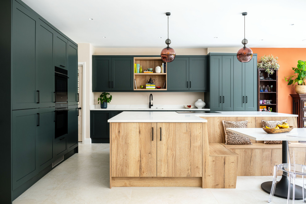 Photo of a large l-shaped kitchen/diner in London with shaker cabinets, green cabinets, quartz worktops, an island, beige floors, white worktops, a submerged sink and black appliances.