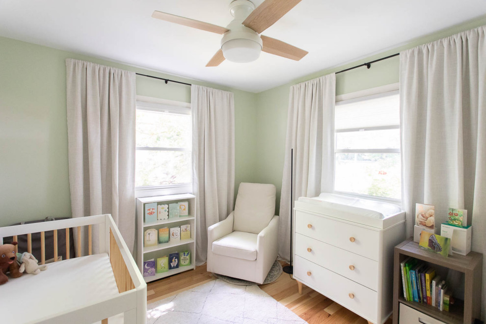 Photo of a small contemporary gender-neutral nursery with green walls and light hardwood floors.